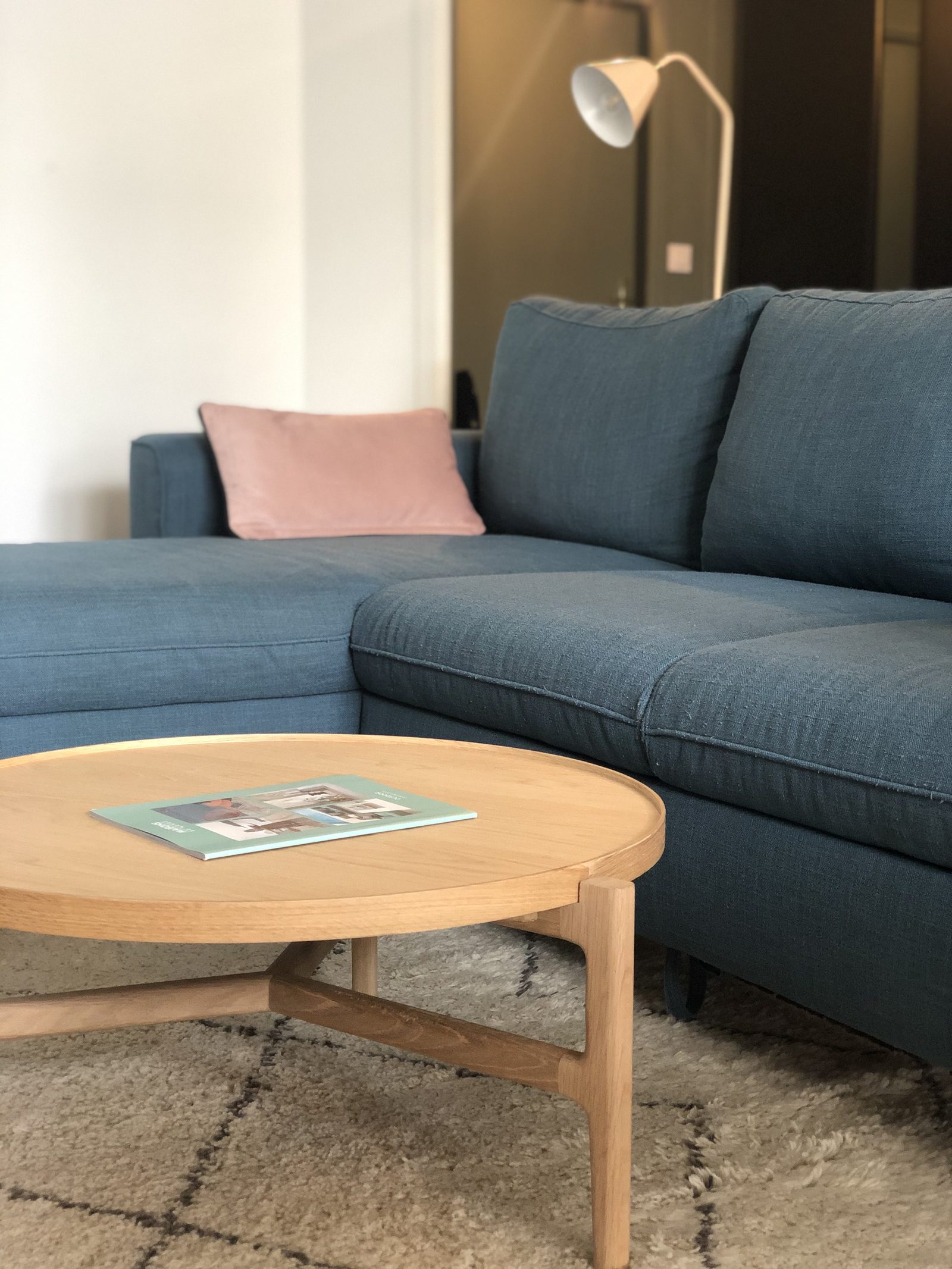 Salon avec canapé bleu, tapis berbère et table basse ronde en bois, projet André Philip à Lyon