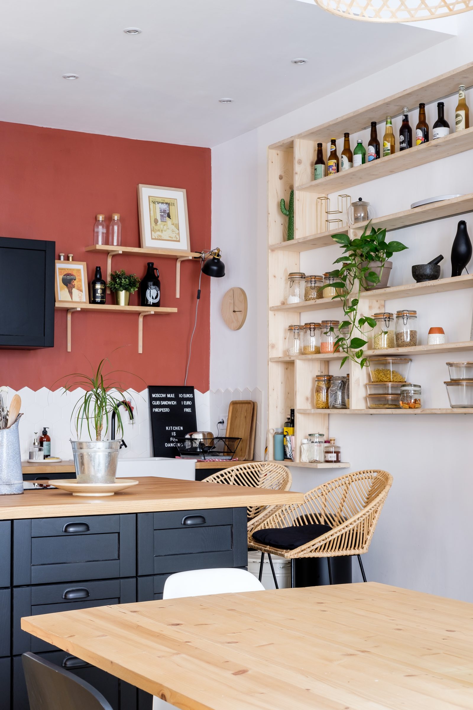 Cuisine ouverte aux façades bleu nuit, mur terracotta et étagères en bois, appartement à la Guillotière