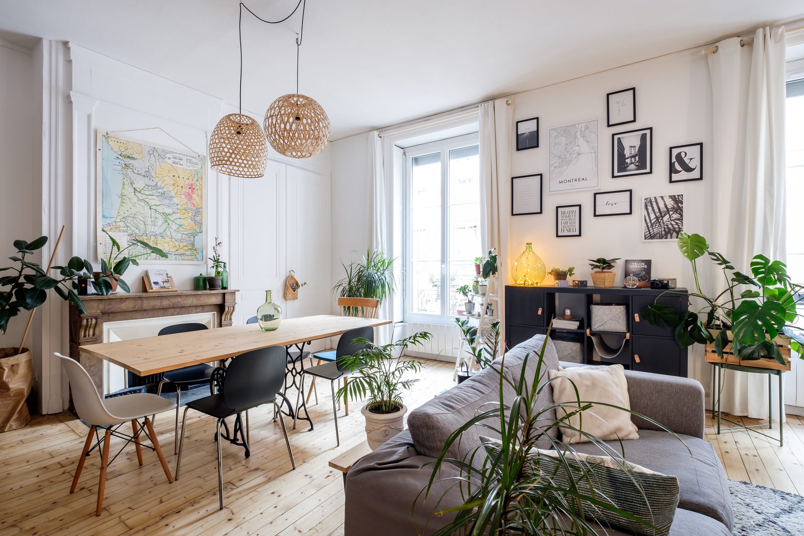 Coin repas avec grande table en bois, carte ancienne et suspension en rotin, appartement à la Guillotière