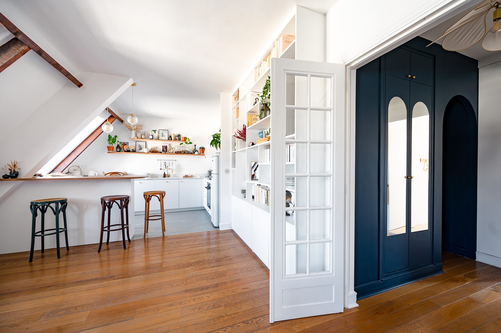 Cuisine ouverte bois et blanc avec portes d'atelier bleu profond sous les poutres, Saint-Germain-en-Laye